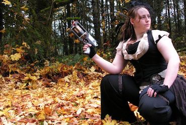 Kirsten in steampunk wear on autumn leaves, crouching and holding a Maverick